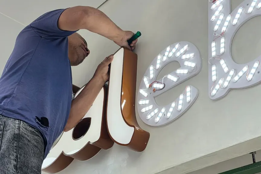 Letras iluminadas da Calebito sendo instaladas na fachada