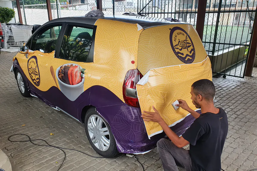Envelopamento de carro em amarelo e roxo sendo aplicado