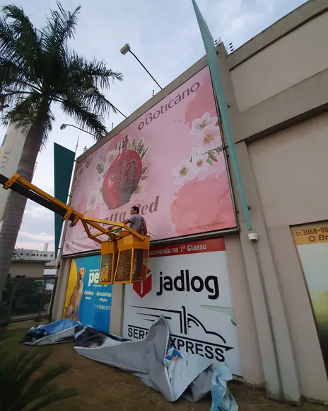 Painel de fachada sendo instalado com plataforma elevatória, ao lado do letreiro da Jadlog